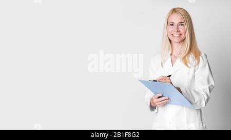 Femme d'âge moyen tenant un diagnostic d'écriture du presse-papiers Banque D'Images