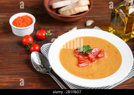 Soupe de légumes avec lentilles sur fond de bois. Servi avec des tomates cerises hachées. À proximité sont des morceaux de ciabatta. Groats bruts en arrière-plan. Banque D'Images