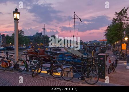 Vélos sur Magere Brug (pont skinny) au coucher du soleil sur la rivière Amstel à Amsterdam, Pays-Bas Banque D'Images