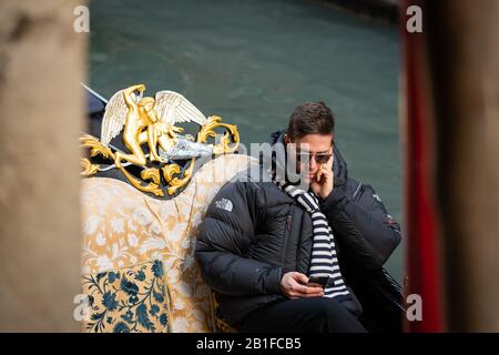 Un gondoliere à Venise (Italie) en attente de clients, à la recherche de son smartphone Banque D'Images