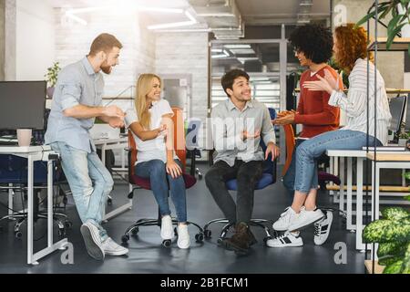 Une équipe joyeuse du millénaire ayant une conversation agréable au bureau Banque D'Images