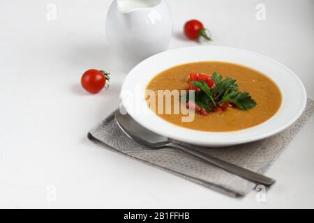 Soupe de légumes avec lentilles sur fond blanc. Servi avec des tomates cerises hachées et des herbes. À proximité sont des morceaux de ciabatta. Gruaux bruts dans le bac Banque D'Images
