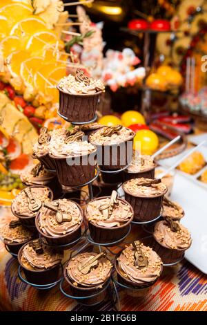 Des cupcakes au chocolat fraîchement préparés, décorés de crème et de boules, se tiennent sur un stand. Atmosphère de vacances, dessert appétissant . Bonbon. Banque D'Images