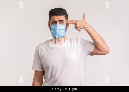 Mortalité du coronavirus. Homme désespéré dans un masque hygiénique pointant le doigt du canon à la tête, peur de l'infection, maladies respiratoires telles que la grippe, 2019-nCoV, Banque D'Images