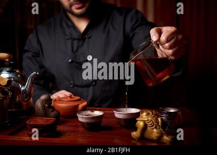 Cérémonie du thé. Un jeune homme verse du thé à partir d'une théière. Banque D'Images