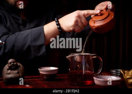 Cérémonie du thé. Un jeune homme verse du thé à partir d'une théière. Banque D'Images