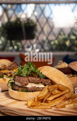 Hamburger maison double avec fromage de chèvre et frites sur table en bois. Image verticale Banque D'Images