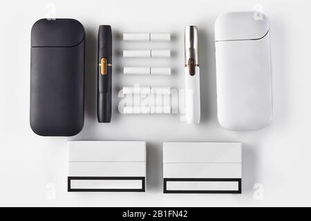 Nouvelle génération, noir et blanc deux cigarettes et batteries électroniques, cinq bâtons de chaleur, paquets isolés sur blanc. Nouvelle technologie alternative. Chauffage Banque D'Images