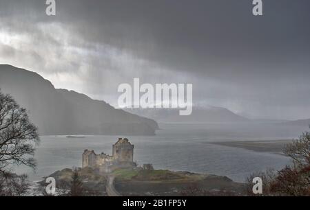 CHÂTEAU D'EILEAN DONAN LOCH DUICH DORNIE ECOSSE HIVER DE LOURDS NUAGES DE TRAÎNEAUX AU-DESSUS DU CHÂTEAU ET DE LA NEIGE SUR LES MONTAGNES Banque D'Images