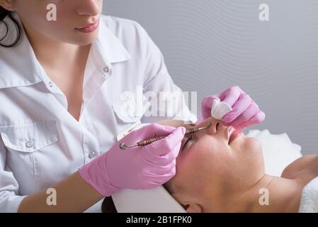 gros plan, mains d'un médecin professionnel de cosmologiste, à l'aide d'un outil, effectue un nettoyage mécanique du visage d'une jeune fille patient. Dans la beauté s Banque D'Images