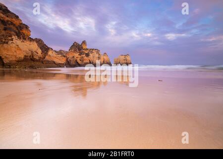 Un coucher de soleil coloré se reflète sur les rives humides de Praia dos Tres Irmaos. Alvor, Portimao, Algarve, Portugal, Europe. Banque D'Images