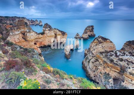 Lever de soleil nuageux sur les falaises jaune et rouge de Ponta da Piedade. Lagos, Algarve, Portugal, Europe. Banque D'Images