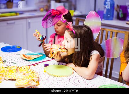 Jolie petite fille mange de la pizza à la fête. Jolie fille en costume de papillon. Fête d'anniversaire Banque D'Images