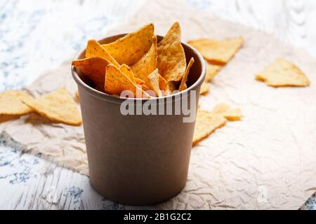 Chips de tortilla dans un bol en papier d'artisanat sur une table en bois rustique, gros plan Banque D'Images