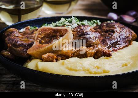 Osso buco avec gremolata, condiment de hacher le cilantro, l'ail, et le zeste de citron, servi avec polenta. Cuisine italienne traditionnelle Banque D'Images