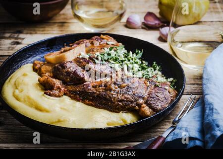 Osso buco avec gremolata, condiment de hacher le cilantro, l'ail, et le zeste de citron, servi avec polenta. Cuisine italienne traditionnelle Banque D'Images