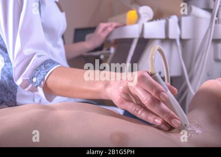 Le médecin utilise une machine à ultrasons pour analyser le cœur d'un patient âgé de sexe masculin. Un médecin à ultrasons examine le cou et l'abdomen d'un enfant à l'aide d'un U. Banque D'Images