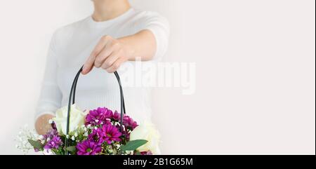 Fille tient un panier de fleurs dans ses mains. Livraison de fleuriste. Espace de copie. Gros plan. Banque D'Images