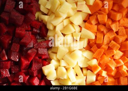 Betteraves, pommes de terre et carottes en tranches brutes carrées sur trois rangées de fond. Vue de dessus. Nourriture végétalienne saine. La vinaigrette Banque D'Images