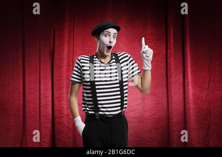 Homme exécutant pantomime sur scène avec des rideaux rouges Banque D'Images