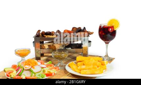 Bœuf et poulet grillés accompagnés de saucisses, de salade et d'un verre de vin sur fond blanc Banque D'Images