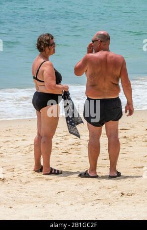 un couple d'âge moyen se tenant sur une plage de patong, thaïlande, bronzer sur la plage de sable au bord de la mer. Banque D'Images