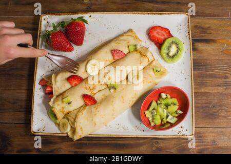 Crêpes saines avec fruits, banane, kiwi et fraise. Petit déjeuner français sain Banque D'Images