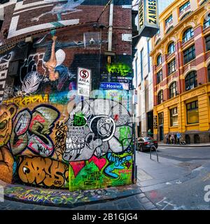 Peinture du crâne et divers dessins peints, la chaussée couverte de graffitis avec la famille qui descend la rue en arrière-plan. Hosier Street, Melbourne Lan Banque D'Images