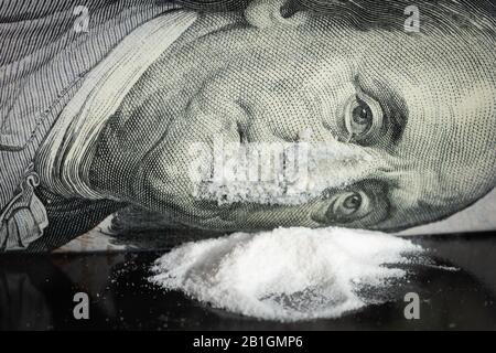 Poudre blanche sous forme de cocaïne sous le nez et la bouche Ben Franklin, facture de cent dollars. Concept de stupéfiants. Banque D'Images