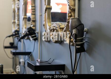 sèche-cheveux sur un stand dans un salon avec les miroirs de salon de coiffure accrochés sur les murs Banque D'Images