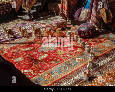 Une parade de petits chameaux dans un demi-cercle sur un tapis persan avec des tentures et des tabourets tapisserie derrière Banque D'Images