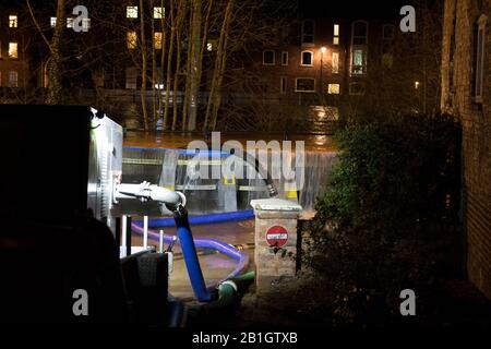 Bewdley, Royaume-Uni. 25 février 2020. Les niveaux de la rivière atteignent un sommet sans précédent ce soir à 21:30, alors que les eaux d'inondation commencent à se déverser dangereusement au-dessus des barrières de défense contre les inondations à Beale's Corner dans la ville de Worcestershire de Bewdley. Des services d'urgence sont présents toute la nuit pour s'assurer que les pompes à eau industrielles sont utilisées en permanence en pompant le plus d'eau possible dans la rivière Severn et loin des propriétés périlleusement proches à risque. Crédit: Lee Hudson/Alay Live News Banque D'Images