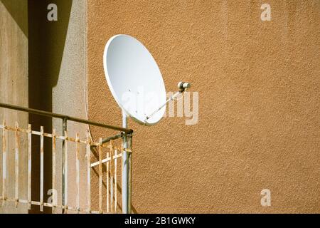 Un plat satellite blanc est installé sur une rampe de balcon Banque D'Images