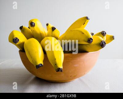 De nombreuses bananes jaunes dans un bol en céramique marron sur la table, vue de côté. Banque D'Images
