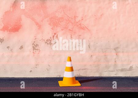 Graphique d'ordinateur tridimensionnel, cône de signalisation rouge à rayures blanches contre un mur rougeâtre Banque D'Images