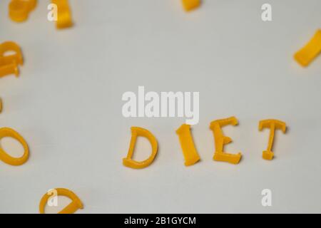 Le régime des mots se compose de lettres comestibles. Alimentation Des Pâtes Alimentaires. Pâtes sous forme de lettres sur fond gris. Concept de nutrition approprié. Espace de copie Banque D'Images