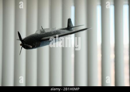 Un vieux avion modèle poussiéreux (Grumman Avenger) accroché au plafond de la chambre d'enfants avec des stores ouverts comme toile de fond. Banque D'Images