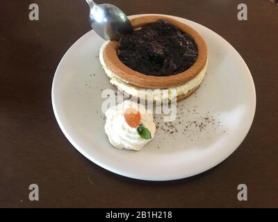 Gros plan sur un délicieux cheesecake blackberry avec crème fouettée et abricot dans le coin de la plaque de céramique blanche sur une table en bois. Banque D'Images