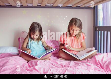 Joyeuses soeurs caucasiennes filles lisant des livres dans la chambre. Enfants frères et sœurs à la maison passer du temps ensemble. Apprentissage du développement de l'éducation des enfants. pe réel Banque D'Images