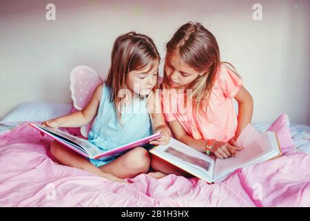 Joyeuses soeurs caucasiennes filles lisant des livres dans la chambre. Enfants frères et sœurs à la maison passer du temps ensemble. Apprentissage du développement de l'éducation des enfants. pe réel Banque D'Images