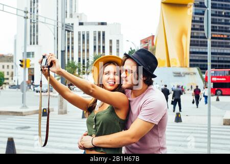 Portrait d'un jeune couple en riant s'amuser à prendre selfie dans la rue du centre de Mexico Banque D'Images