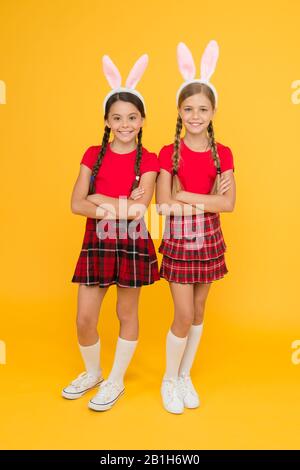 Uniforme scolaire pour petites écolières avec de longues oreilles de lapin. Jeux traditionnels de Pâques. Équipe de Bunny. Concept de divertissement et d'événement. Vacances de printemps. Enfants dans les oreilles de lapin de lapin. Famille et Sisterhood. Banque D'Images