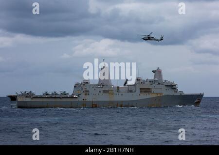 MER des Philippines (janv 29, 2020) le quai de transport amphibie USS Green Bay (LPD 20) transite l'océan ouvert tandis qu'un Seahawk de MH-60 avec les 'Island Knights' du Escadron de combat en mer d'hélicoptère 25 vole en hauteur. Greenbay, qui fait partie du America Expeditionary Strike Group, 31 Meu Team, opère dans la 7ème zone d'opérations de la flotte des États-Unis pour améliorer l'interopérabilité avec les alliés et les partenaires et servir de force d'intervention prête pour défendre la paix et la stabilité dans la région d'Indo-Pacifique. (Photo officielle du corps marin des États-Unis par le Cpl lance. Joshua Sechser) Banque D'Images