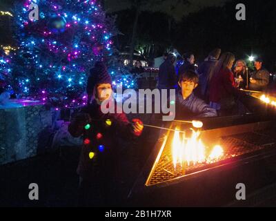 Deux enfants qui toasting des guimauves au parc de la ville pendant la saison de Noël. La Nouvelle-Orléans, LA. Banque D'Images