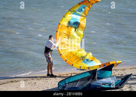 Ninh Chu Beach, province de Ninh Thuan, Vietnam - 9 janvier 2020: Un homme avec un grand cerf-volant jaune sur une plage à Ninh Chu. Le kite surf est un sport qui est Banque D'Images