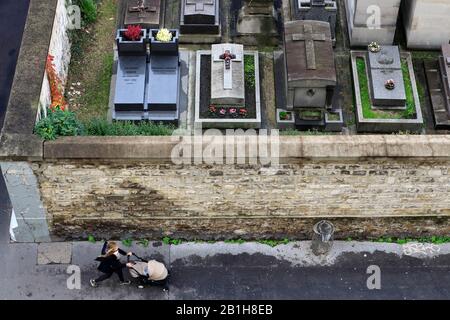 Vue imprenable sur une femme marchant au mur du cimetière de Montmartre avec le cimetière de Montmartre en arrière-plan.Paris.France Banque D'Images