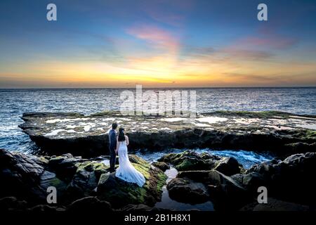 Hang Rai Coral Beach, Phan Rang City, Vietnam - 10 Janvier 2020: Mariée et marié heureux de prendre des photos souvenirs sur les grandes roches de la plage. Concept pour Banque D'Images