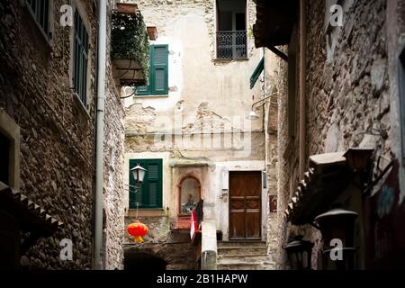 Une allée sombre pittoresque avec une porte et une alcôve avec statue dans le village médiéval perché de Dolceacqua, Italie. Banque D'Images