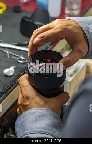 Technicien avec un doigt amputé et un objectif de caméra de nettoyage Banque D'Images