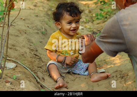 Portrait en plein air d'un joli enfant asiatique ou indien avec une heureuse expression faciale souriante jouant avec du sable et regardant la nature et montrant quoi
